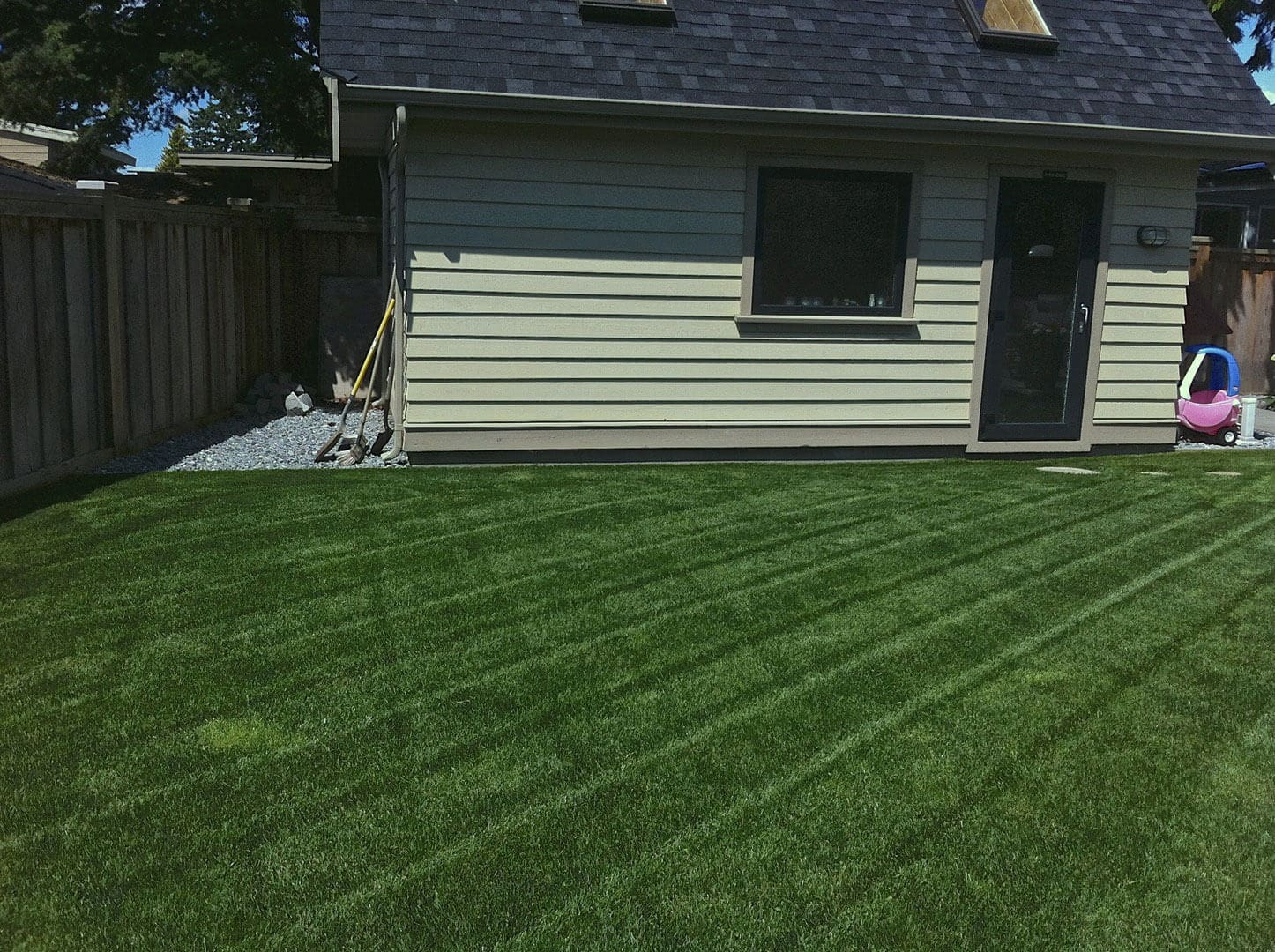 Freshly mowed lawn with striped grass in front of a small building.