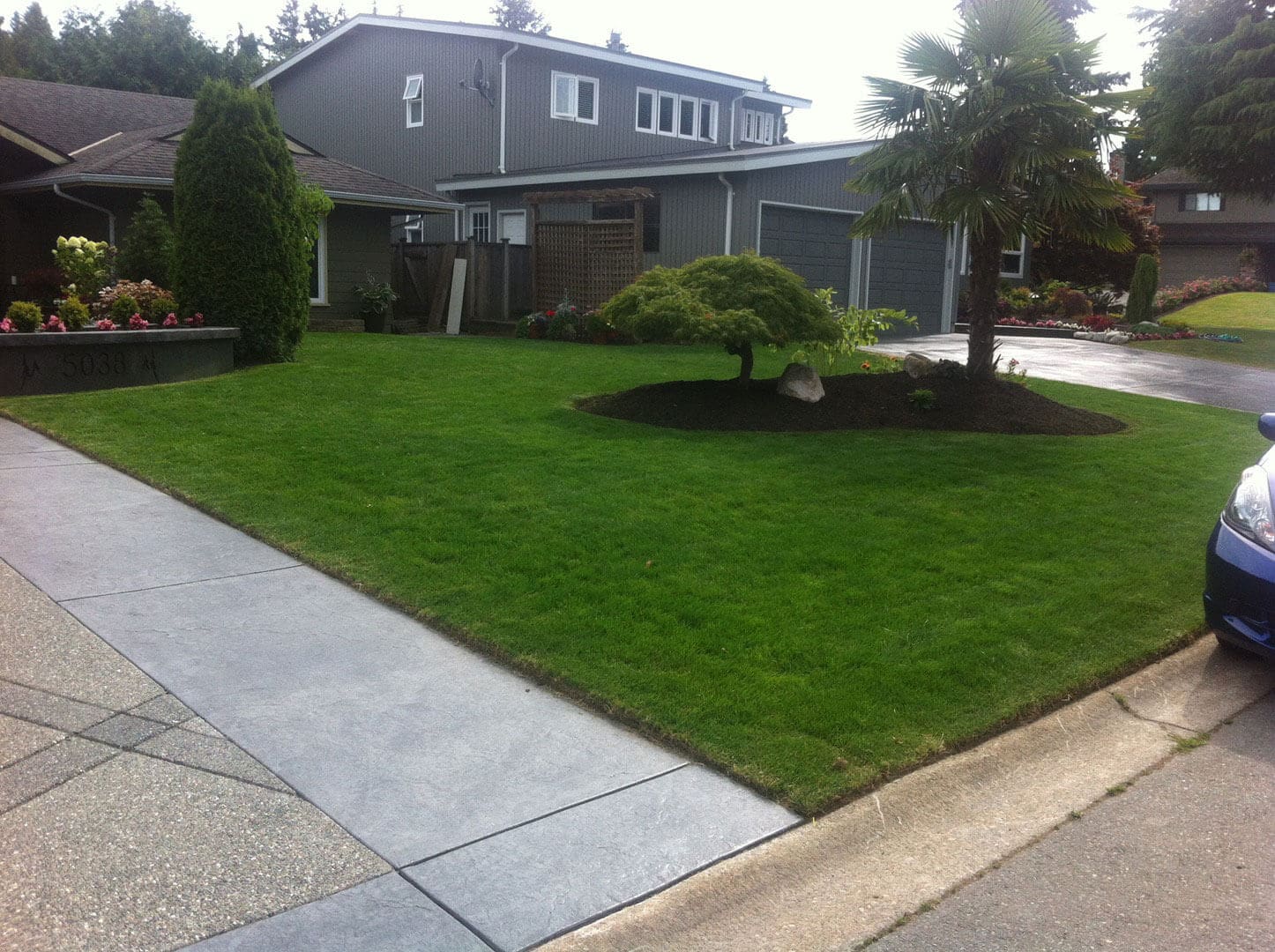 A well-maintained suburban house with a green lawn and landscaped garden.