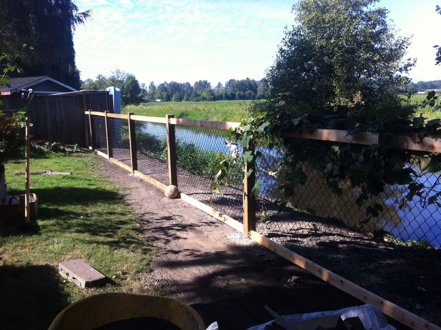 A wooden footbridge over a calm river surrounded by greenery.