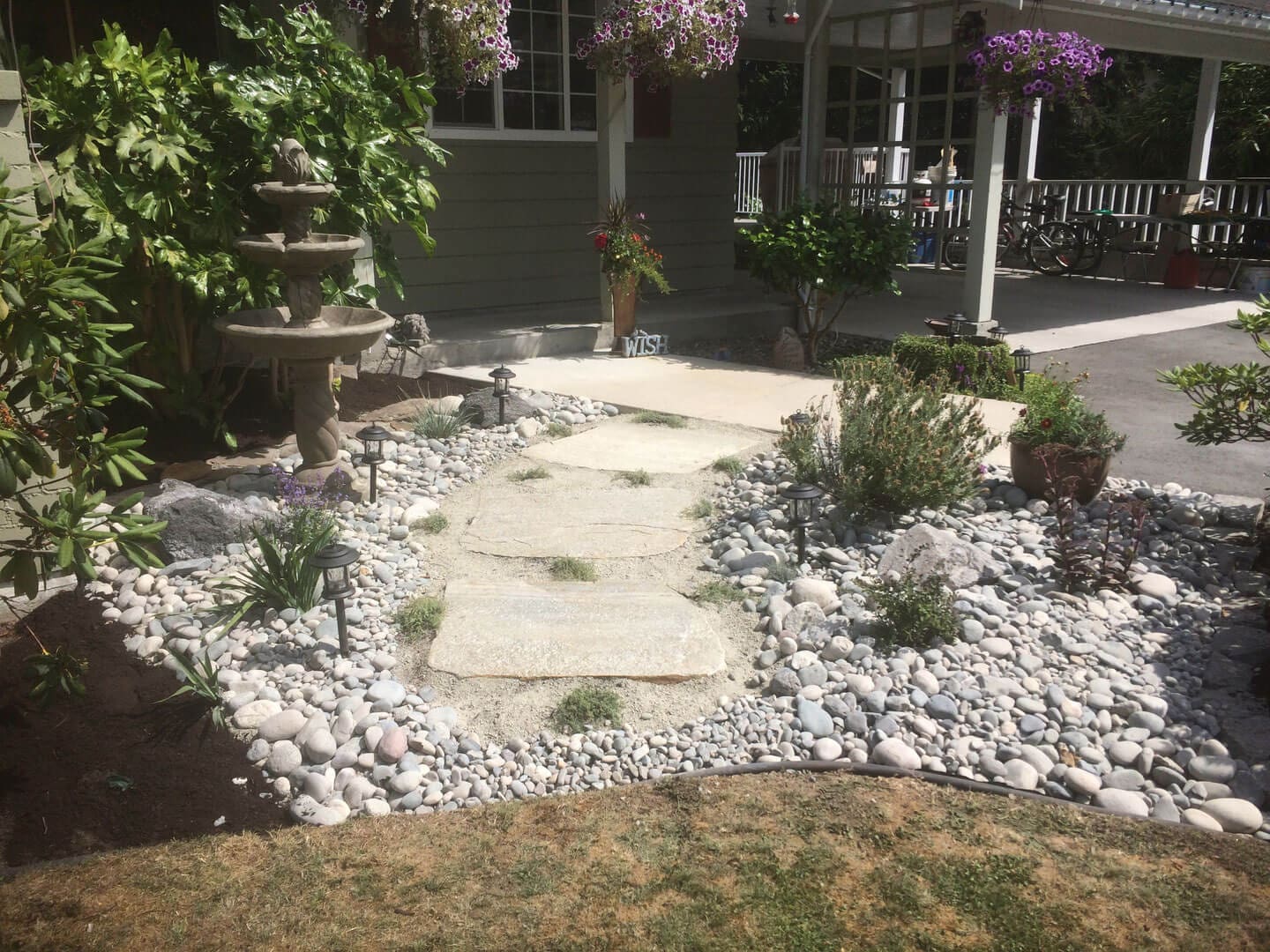 A stone pathway bordered by white rocks leading to a garden area.